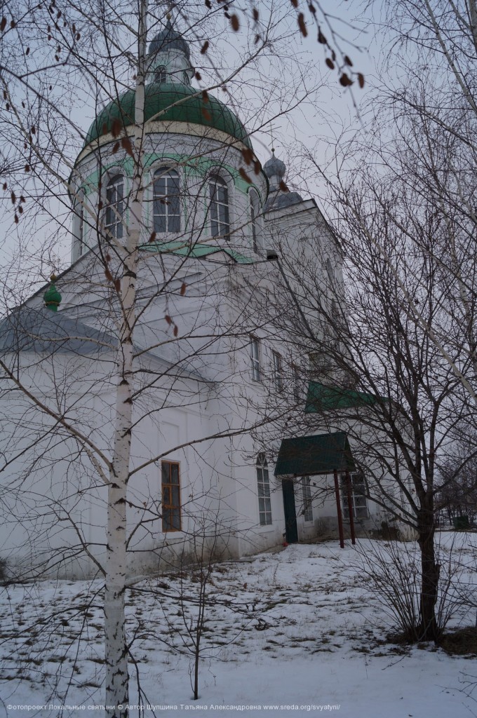 Вид на каменную церковь сквозь березы